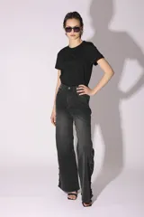 Pantalón de jean gris oscuro con lavado gastado, corte acampanado y tachas plateadas en los laterales.