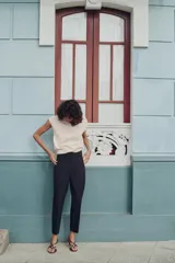 Pantalón largo negro con finas rayas verticales blancas, de tiro alto y corte recto.