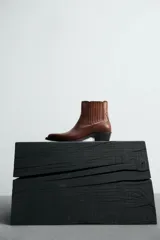 Bota de cuero color marrón, estilo cowboy, con caña corta, puntera en punta y tacón cubano.