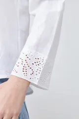 Camisa blanca de manga larga con cuello y puños bordados con calados. Corte clásico y cierre frontal con botones.
