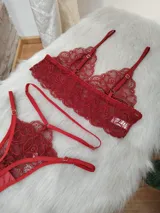 Conjunto de lencería de encaje rojo, compuesto por un bralette triangular sin aros y una tanga. Ambas piezas presentan un diseño floral de encaje y tirantes finos ajustables.
