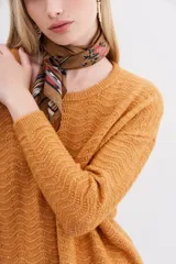 Sweater color mostaza de tejido de punto con detalle de lentejuelas integradas al hilado, calce holgado y mangas largas.