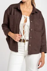 Sobrecamisa color verde militar, de corte oversize, con cuello camisero, cierre frontal con botones y bolsillos de parche en el pecho. Confeccionada en gamuza de cuero vegano.