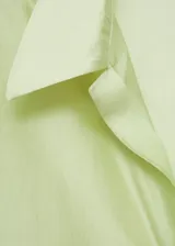 Camisa azul eléctrico de tejido satinado, corte recto, cuello camisero, manga larga con puños abotonados y cierre frontal con botones.