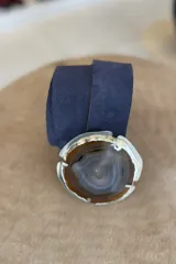 Cinto de cuero azul con hebilla circular de piedra ágata con borde dorado.