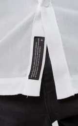 Camisa blanca de manga larga con cuello mao y cierre frontal con botones.