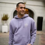 Canguro lila con capucha ajustable con cordón, bolsillo tipo canguro al frente y terminaciones acanaladas en puños y pretina. Estampado circular con el logo de la marca en el pecho.