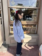 Camisa celeste y blanca a rayas verticales, de corte amplio y mangas largas con puños anchos.