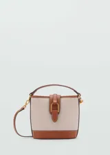 Bolso tipo bucket color crudo con base marrón, confeccionado en tejido mezcla de algodón con efecto rafia. Tiene asa corta superior, asa larga desmontable y cierre de solapa con botón magnético.