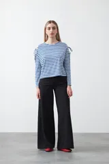 Remera de manga larga a rayas horizontales blancas y negras, con escote redondo y aberturas en los hombros sujetas con lazos regulables de tela a rayas.