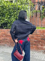 Campera de jean azul oscuro con costuras en hilo ocre, corte recto, cuello clásico, bolsillos frontales con solapa y cierre con botones metálicos.