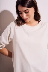 Remera color crema de algodón peinado, con mangas 3/4 abullonadas y corte ajustado al cuerpo.