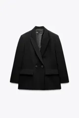 Blazer negra oversize con cuello solapa, manga larga con hombreras y bolsillos delanteros con solapa. Cierre frontal cruzado con botones.