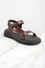 Sandalias de cuero color marrón con textura tipo cocodrilo, plataforma plana y tira ajustable con hebilla.