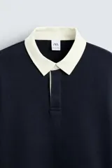 Sudadera azul marino de corte regular con cuello polo blanco de solapa y cierre frontal de botonadura oculta.