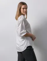 Camisa texturada blanca con líneas verticales negras, marca Hester & Orchard. Cuello a la base, escote en V y abertura central con botones. Manga ¾ con terminación fruncida.