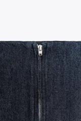 Falda midi de denim azul oscuro, de tiro medio, corte evasé y cierre trasero con cremallera metálica.