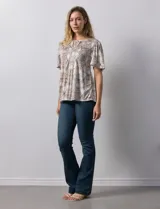 Blusa de tejido elastizado con estampado geométrico en tonos beige y blanco. Tiene cuello redondo con escote en V y lazo de ajuste, y mangas cortas amplias. Marca Cupio.