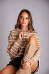 Sweater de punto color beige con rayas horizontales blancas, cuello polo con cierre de cremallera y mangas largas.