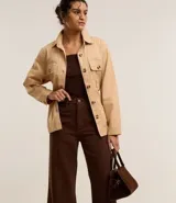 Pantalón wide leg color crudo, de sarga con tiro alto, trabillas, bolsillos delanteros y traseros, y costura vertical delantera.