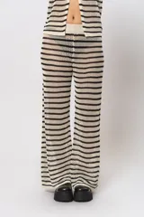 Pantalón tejido a rayas horizontales en hilo de algodón color crudo y negro, con calado abierto, cintura elastizada y corte recto ancho.