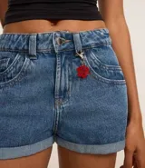 Short de jean de tiro alto, corte slim, con trabillas en la cintura, cierre tradicional, bolsillos y colgante de flor.