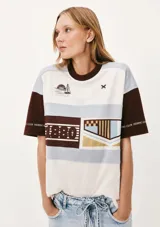 Camiseta de mangas cortas con cuello redondo y corte amplio. Presenta un diseño con bloques de color y estampados con motivos náuticos y geométricos.