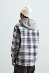 Sobrecamisa de hombre a cuadros azul marino y blanco, corte relaxed fit, con capucha gris de algodón, cuello solapa, manga larga con puños abotonados, bolsillos de parche en el pecho y bolsillos laterales en la cadera.