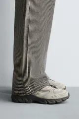 Zapatillas deportivas color crema con cordones, suela gruesa con diseño irregular y detalles en gris.