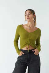 Top rojo de tejido de punto acanalado, con escote en V y mangas largas. Presenta un fruncido ajustable en el centro del frente.