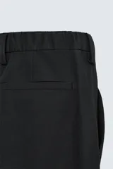 Pantalón de vestir negro de corte recto, con cintura elástica, pliegues frontales, bolsillos laterales y traseros.