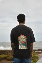 Remera blanca de manga corta con cuello redondo y estampado de tres hongos rojos y la palabra "Tuya" en el frente.