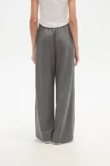 Pantalón deportivo negro de corte ancho y tiro alto, con cintura elástica y cordón ajustable. Presenta una raya blanca vertical a cada lado.