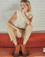 Botines negros de cuero con caña baja, puntera redondeada y cierre frontal con cremallera. Presentan paneles laterales de gamuza y suela track con plataforma.