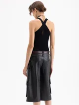 Top de punto acanalado color negro, ajustado al cuerpo y de largo por encima de la cadera. Presenta cuello redondo cerrado y breteles cruzados en la espalda. Confeccionado en hilado frío.