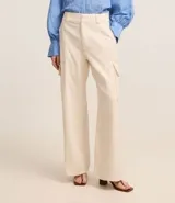 Pantalón wide leg color beige confeccionado en sarga sastrería, de cintura alta, sin estampa y con bolsillos cargo en los laterales.