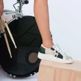 Zapatillas bajas de cuero con paneles en verde, dorado y plateado. Aplique de estrella rosada en el lateral y cordones blancos.