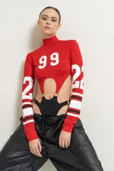 Body de lycra rojo con cuello alto y mangas largas. Tiene aberturas en el abdomen unidas por aros metálicos y estampado con el número 99 en el frente y el número 22 en las mangas.