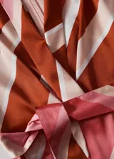 Mono largo de poliéster con estampado a rayas horizontales en tonos rosa, blanco y marrón. Tiene cuello en V, mangas cortas y lazo en la cintura.