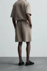 Bermuda color arena de tejido interlock de algodón con elasticidad, corte relaxed fit, cintura elástica ajustable con cordón interior, bolsillos laterales y bolsillo trasero de plastrón.