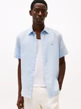 Camisa celeste de lino con corte regular, manga corta, cuello abotonado y logo de Tommy Hilfiger bordado en el pecho.