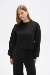 Buzo negro de corte cropped, con cuello redondo y mangas largas abullonadas.