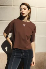 Remera negra de algodón con corte cuadrado, cuello redondo y logo bordado en color naranja.