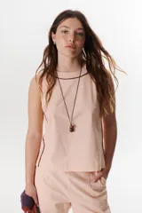Top sin mangas color rosa pálido, con cuello redondo y vivos en color marrón oscuro en el cuello y a lo largo de las costuras laterales.