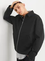 Campera tipo sobrecamisa negra con cierre de cremallera, cuello clásico, mangas largas con puños abotonados y bolsillos frontales. Confeccionada en tejido plano de poliéster reciclado.