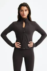 Campera deportiva corta color marrón, de corte ajustado, con cuello alto, cierre frontal con protección para el mentón y mangas largas con abertura para el pulgar. Confeccionada en tejido funcional SoftMove™ y DryMove™.