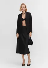 Blazer negro entallado de poliéster, viscosa y elastano, con solapas de muesca, forro interior, abertura posterior, hombreras estructuradas y bolsillos de ribete. Ideal para looks de oficina o eventos formales.