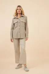 Camisa estilo leñador color beige con textura de espiga, de manga larga con puños abotonados, cuello clásico, cierre frontal con botones y dos bolsillos de parche con solapa abotonada en el pecho.