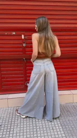 Pantalón de jean celeste de tiro medio con pierna extra ancha y caída fluida, con bolsillos delanteros y traseros, y cierre frontal con cremallera y botón metálico.