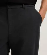 Pantalón de sastrería color gris claro, de corte recto y tobillero, con cintura elástica y cierre frontal.